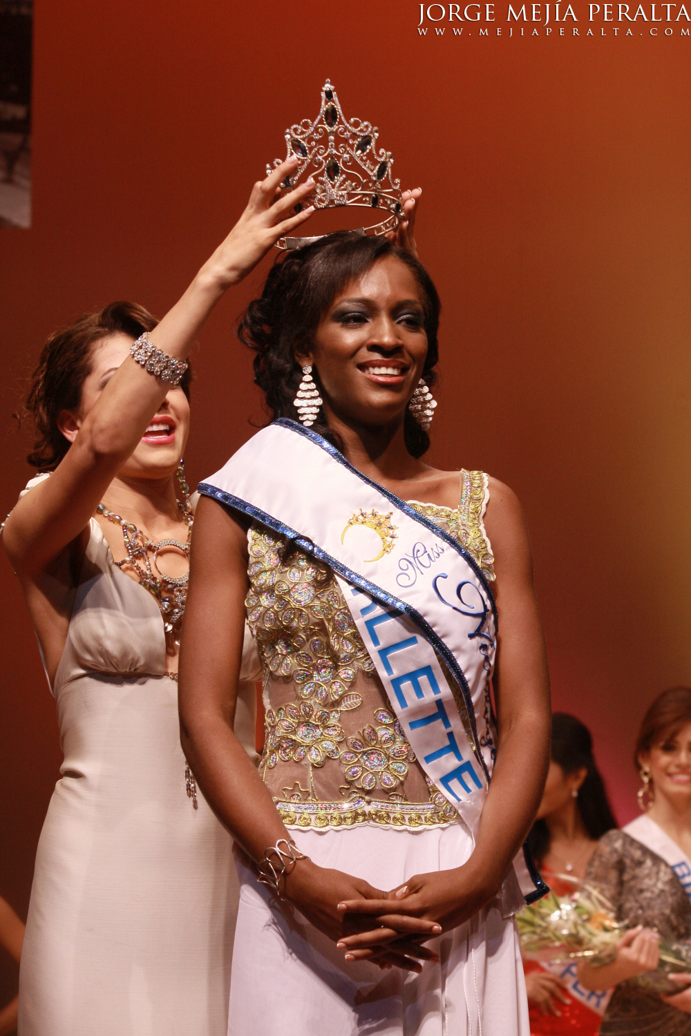 two women on stage with one placing a crown on the other