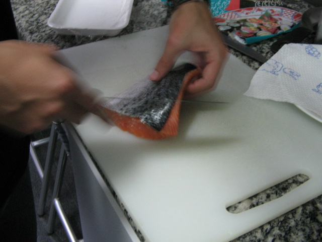 there is someone that is peeling salmon in the kitchen