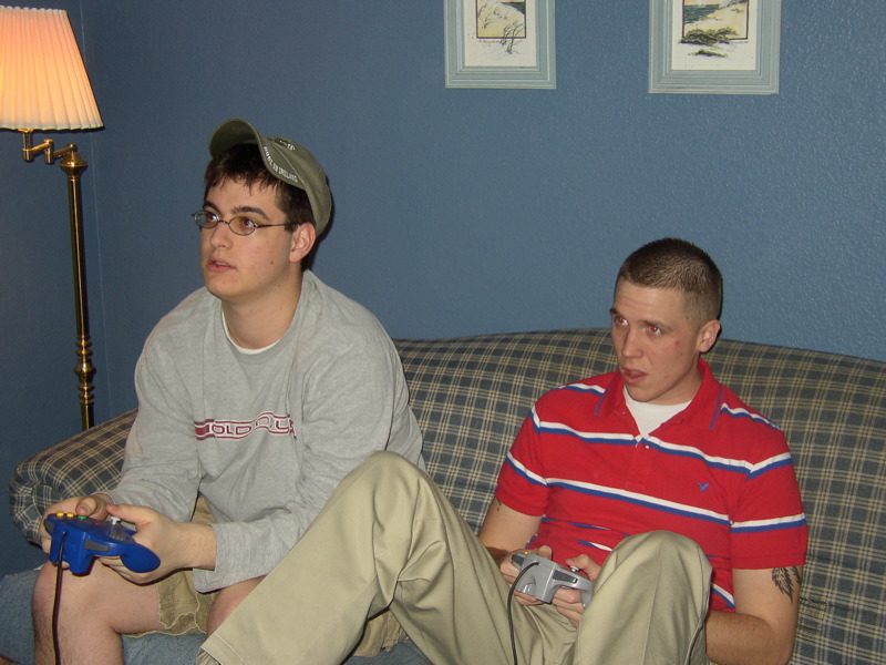 two men sitting on a couch playing a game