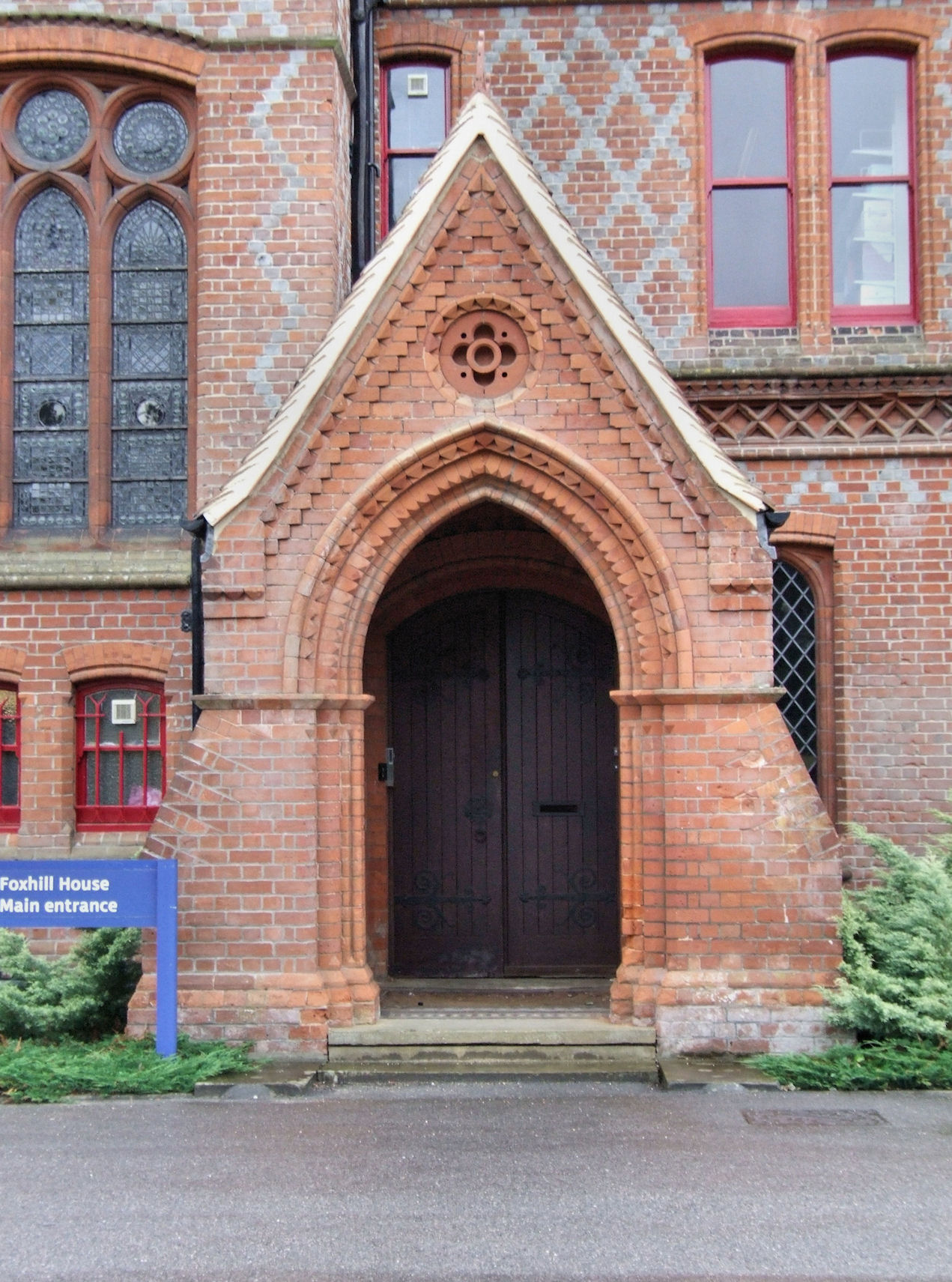 a church with large red brick doors and a blue sign