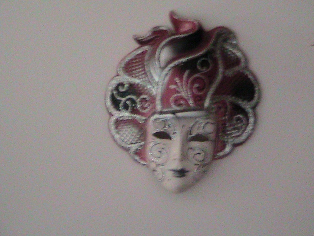 a masquerade mask hanging on a wall in an ornate design