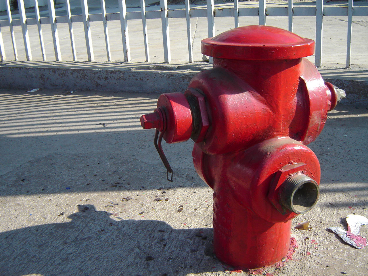 a fire hydrant on the sidewalk outside of an enclosure