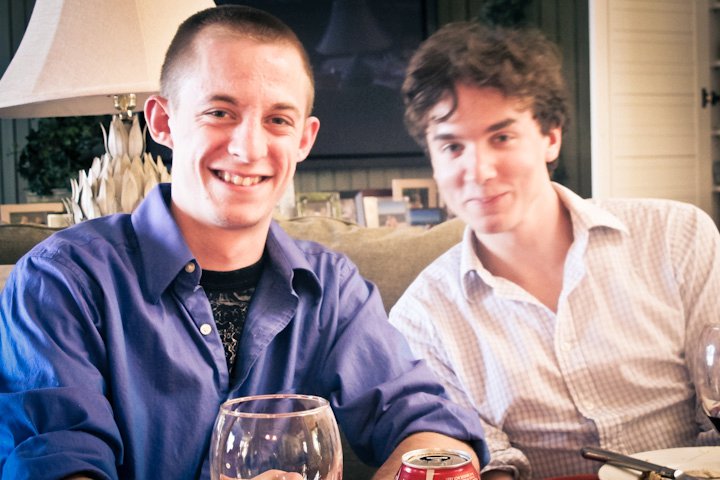 two young men seated at a table holding wine glasses