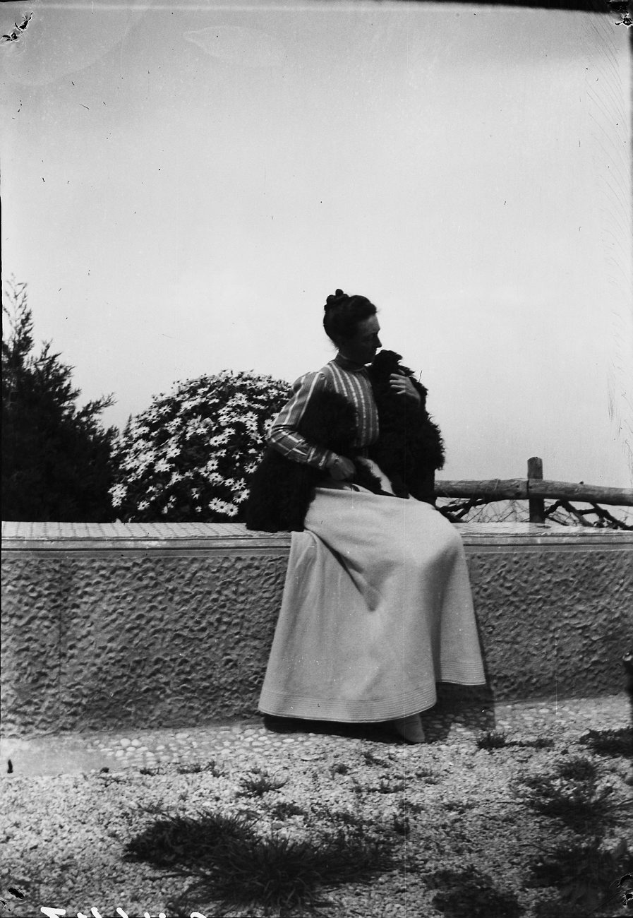 an old black and white po of a woman sitting on a fence