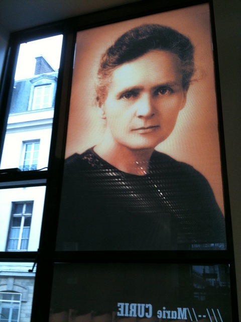 the poster depicts a po of marie curie in paris