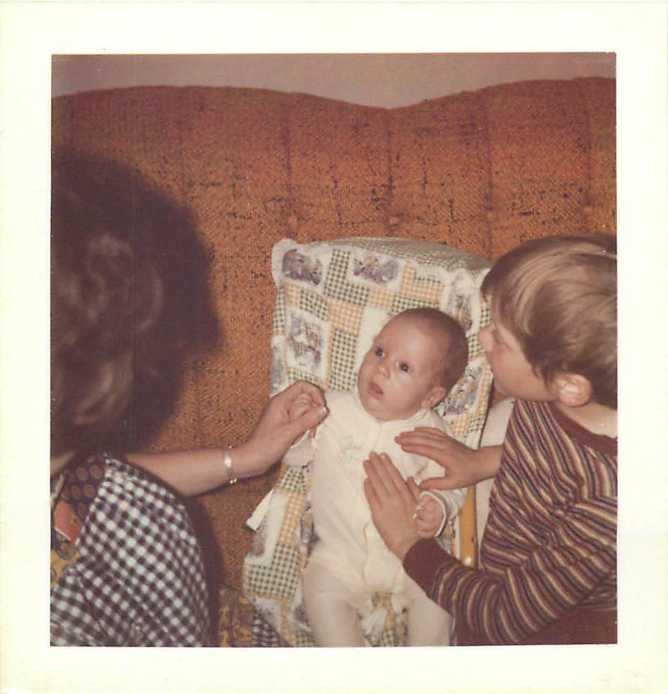 a woman holding a baby on the arm of a chair