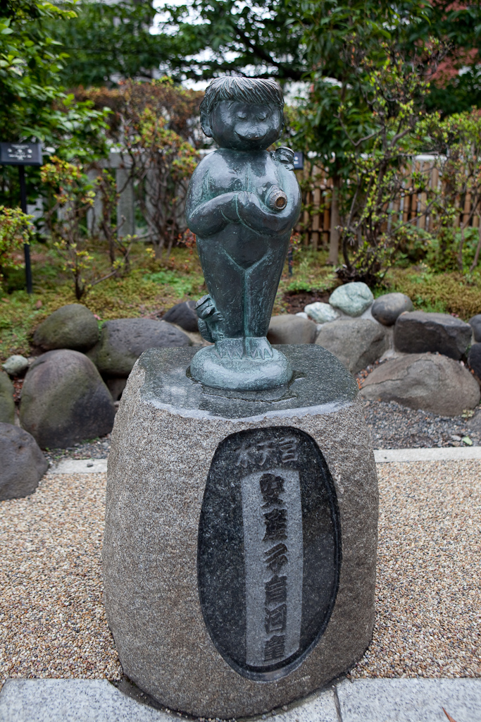 a statue sitting on a stone surface with a rock border around it