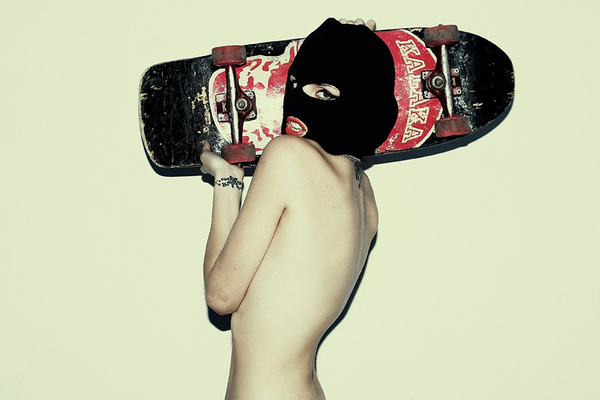 a shirtless man holding a skateboard upside down