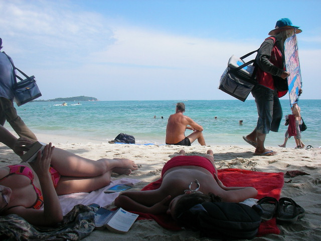 some people on the beach with bags and towels