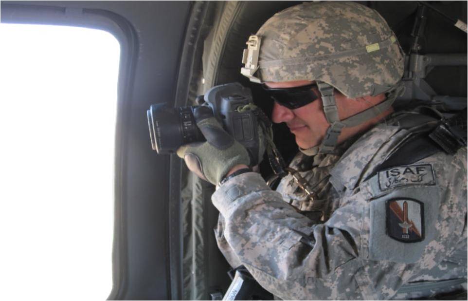 a soldier holding a camera looking out the window