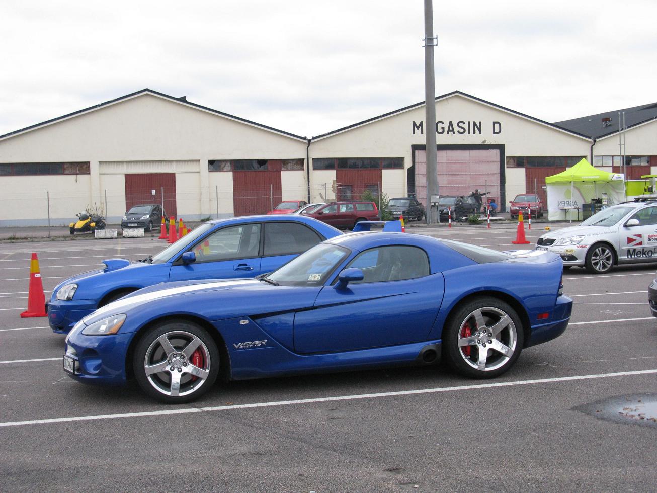 a couple of blue sports cars parked in a lot