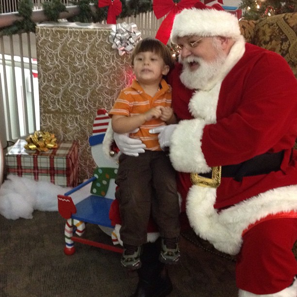 a child dressed as santa and a man sitting on a chair