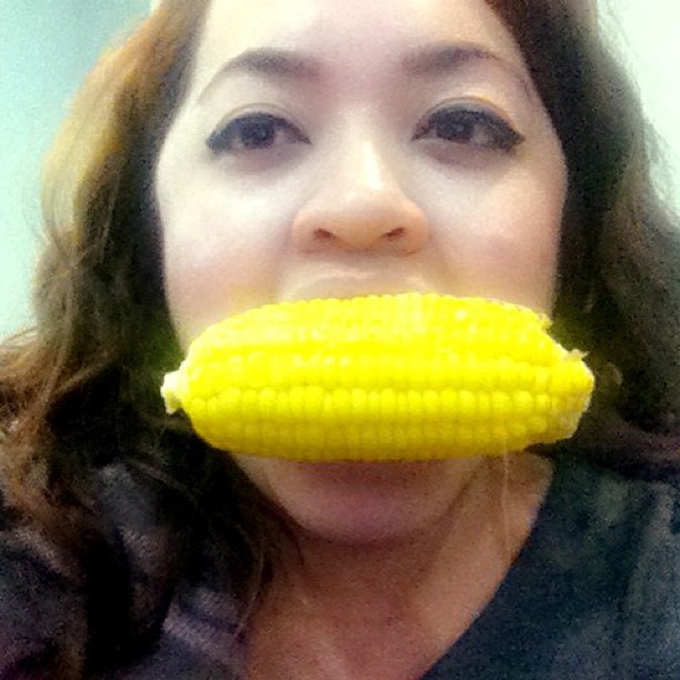 a woman holding a corn cob up to her mouth