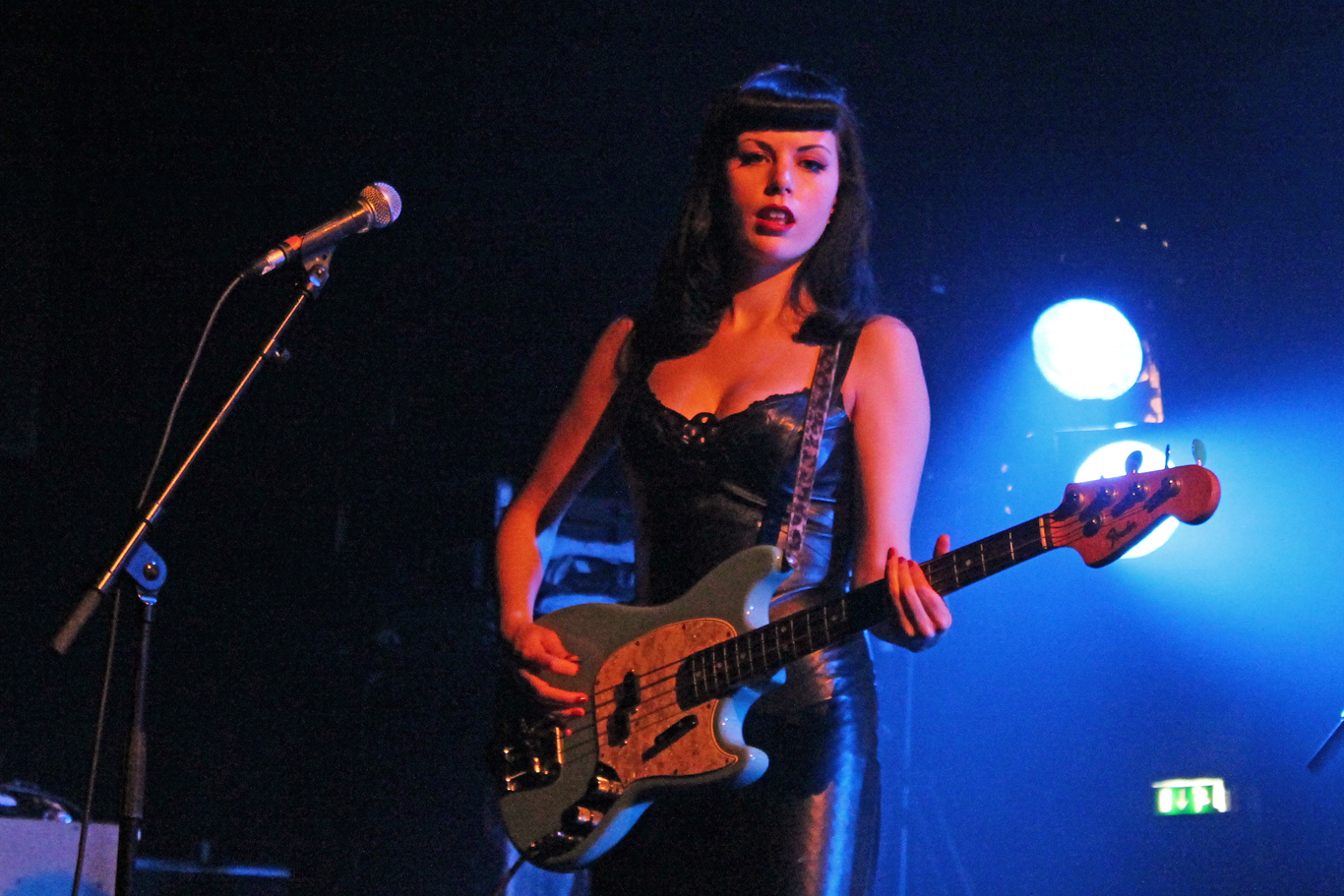 a woman playing on an electric guitar while standing in front of microphones