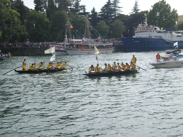 three boats with people in it moving along a river