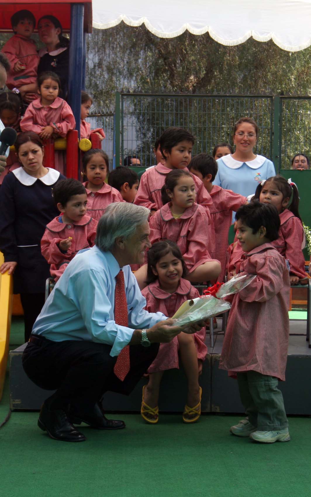 an old man giving out children in front of a crowd