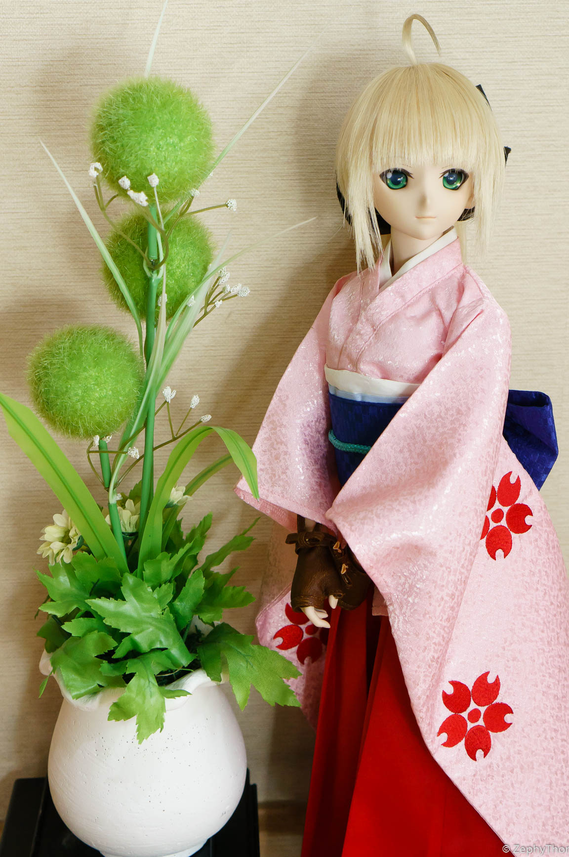 a doll dressed in an oriental fashion next to a vase with plants
