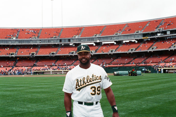 a baseball player poses in the grass while onlookers watch from the bleachers