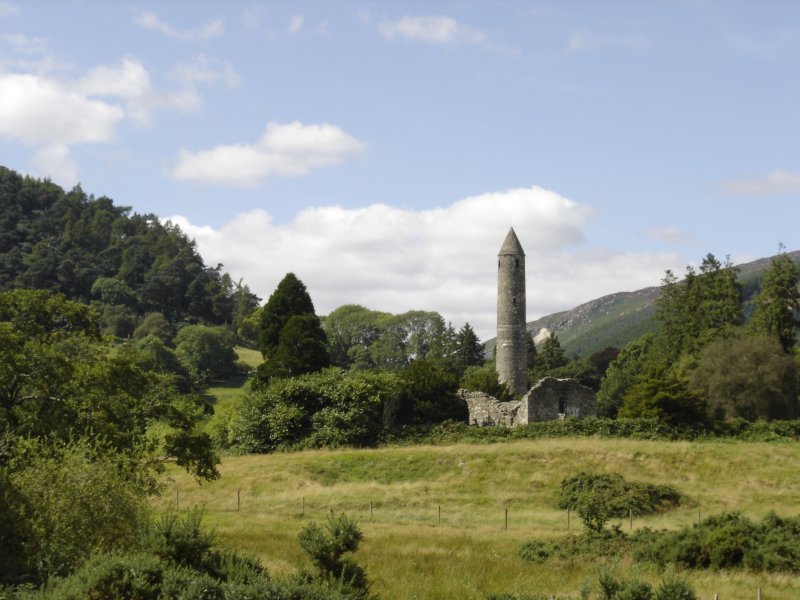 a stone tower in the middle of a grassy field