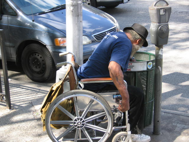 a man hing a wheelchair next to parking meters