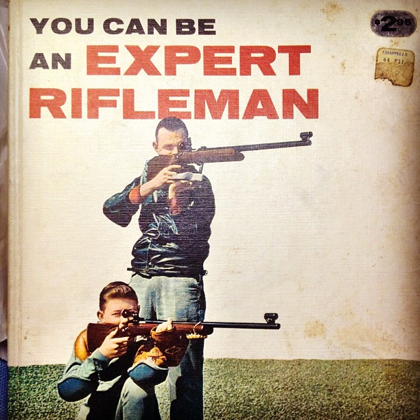 a book cover with two people with guns in the grass