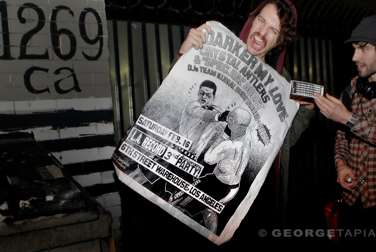 two men holding up a poster advertising a concert