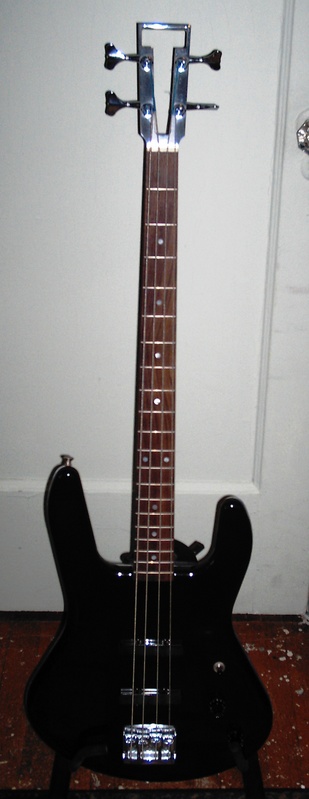 a black guitar standing in front of a white door
