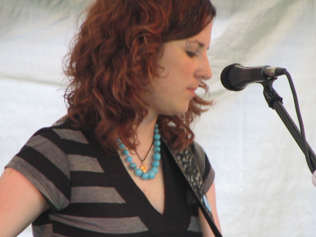 woman wearing a black striped shirt while singing at a microphone