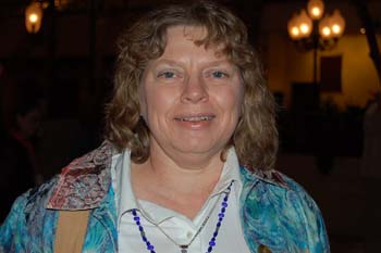 a woman in blue jacket and necklace posing for a picture