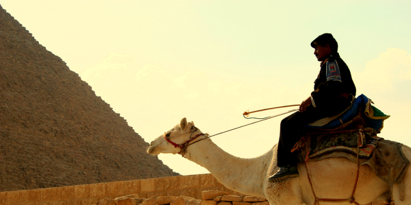 a man is riding a camel and wearing a brown and black hat