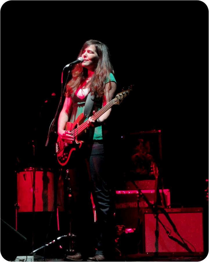 woman with long hair in concert, playing guitar