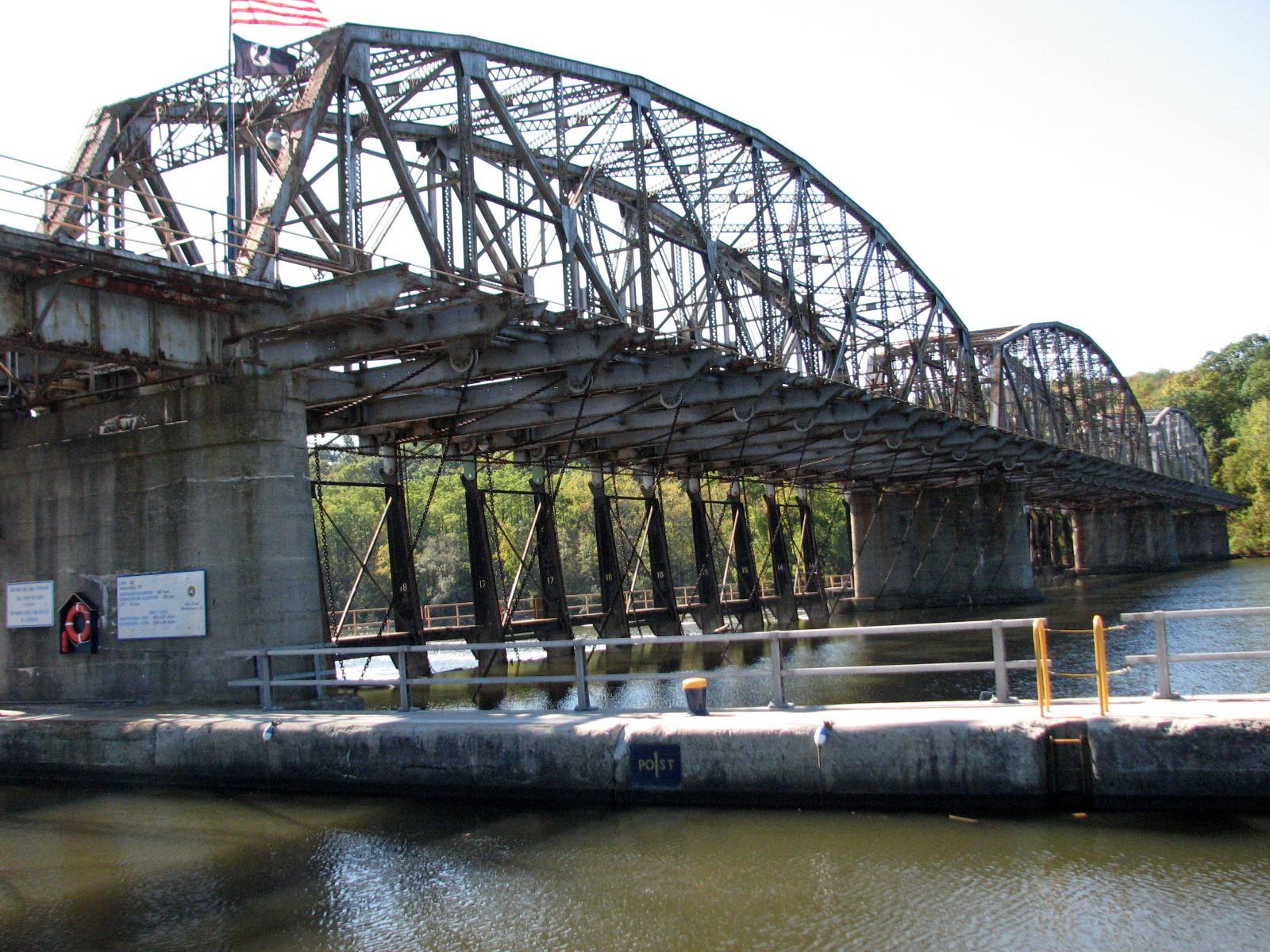 a very old bridge over a river with an american flag flying from it