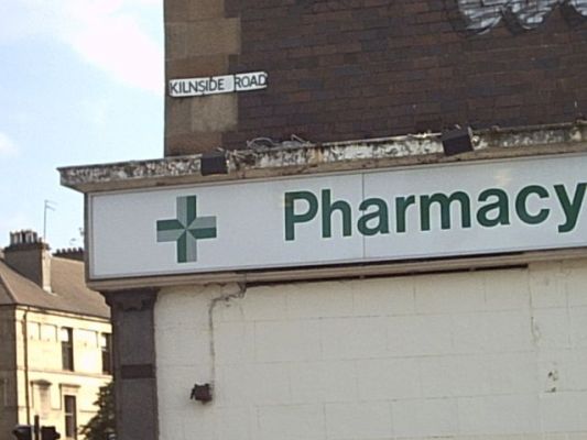 the pharmacy sign outside of a building next to a brick wall