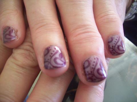 a woman's nail with purple polish and silver design