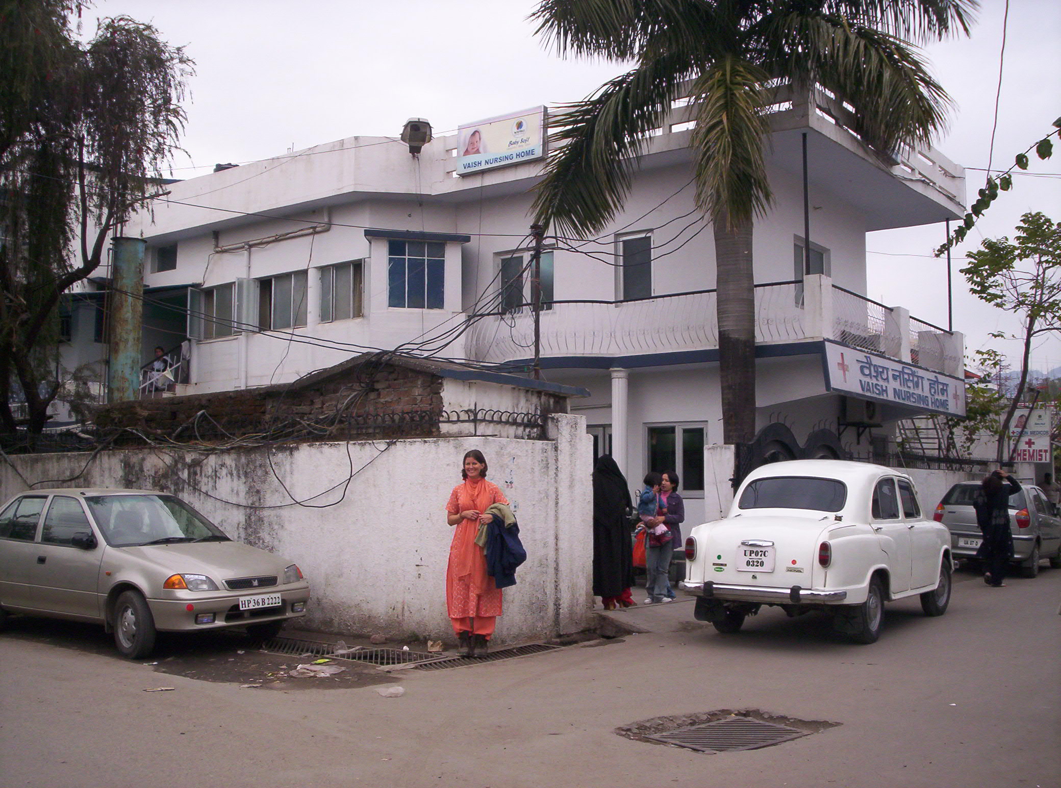 women dressed in colorful clothing outside a white building with parked cars