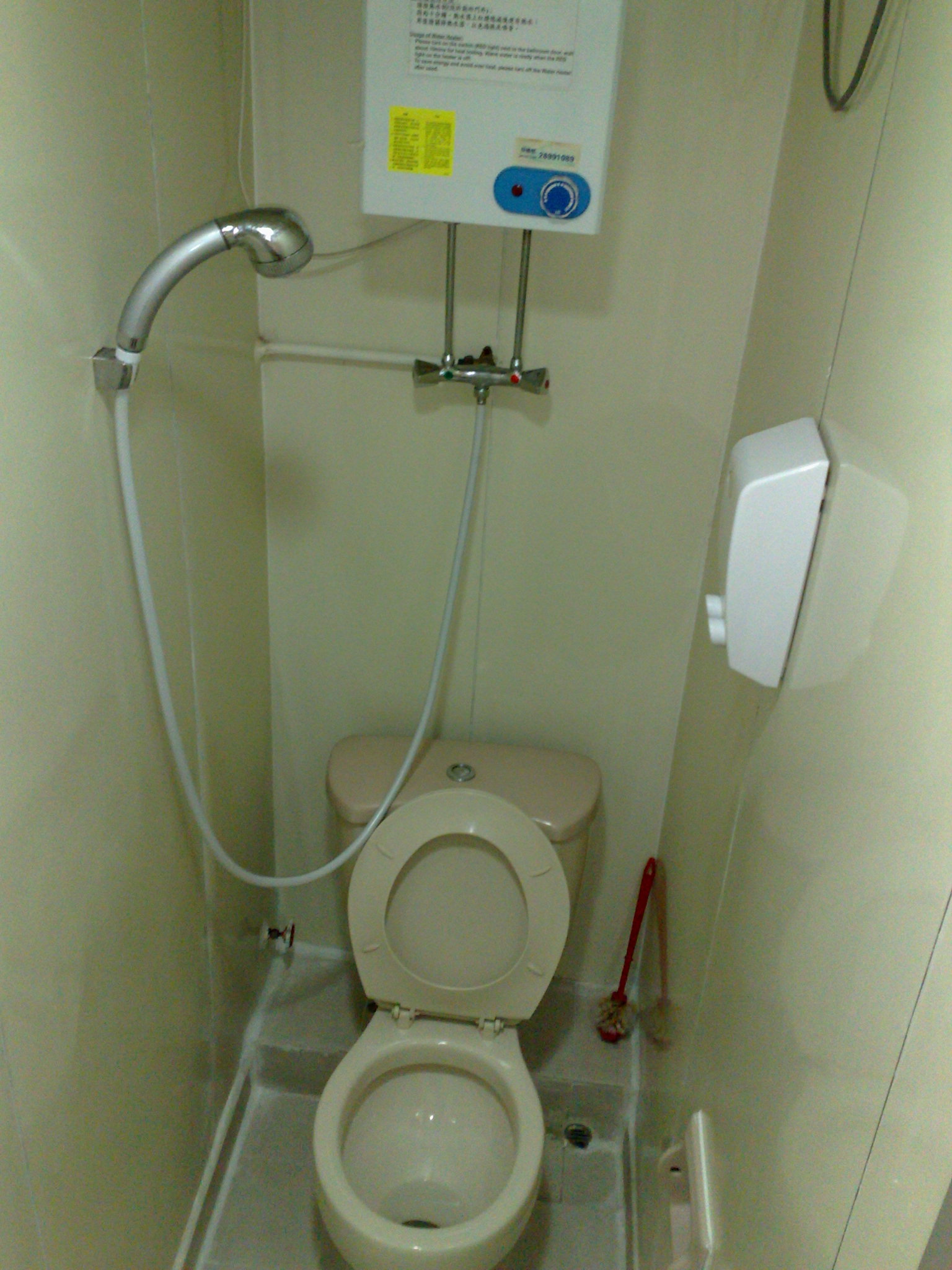 a white toilet sitting next to a shower with a hose attached to the top