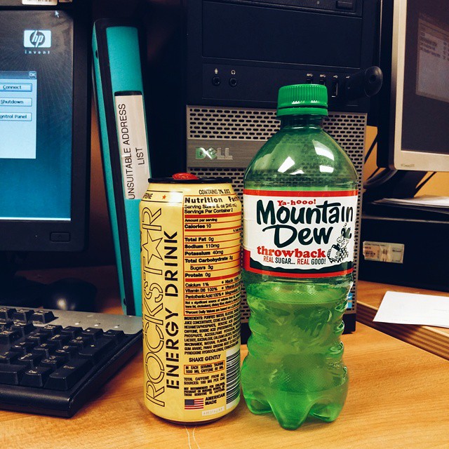 a bottle and a can next to a keyboard