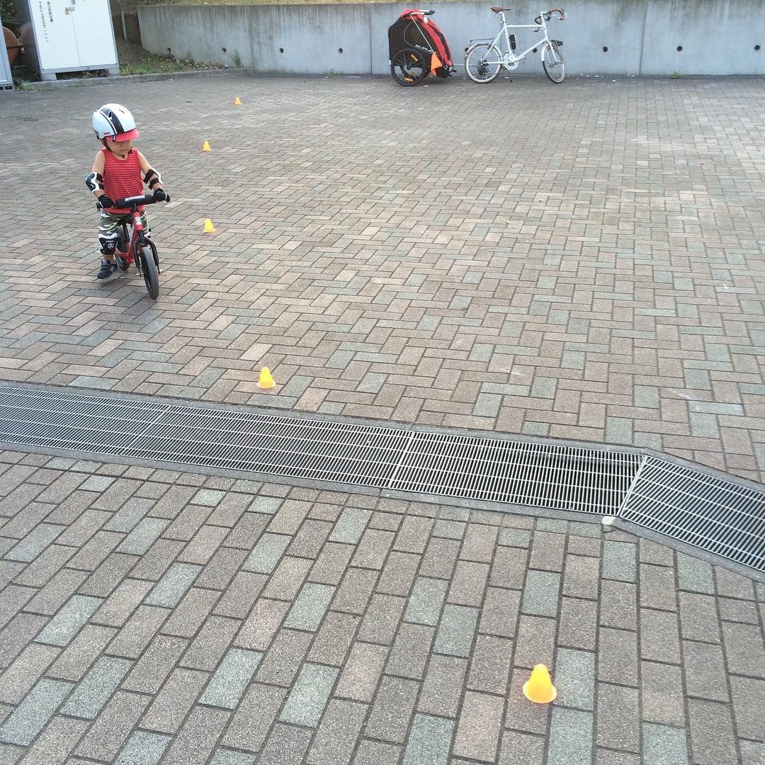 small boy sitting on bicycle parked in front of a fenced area