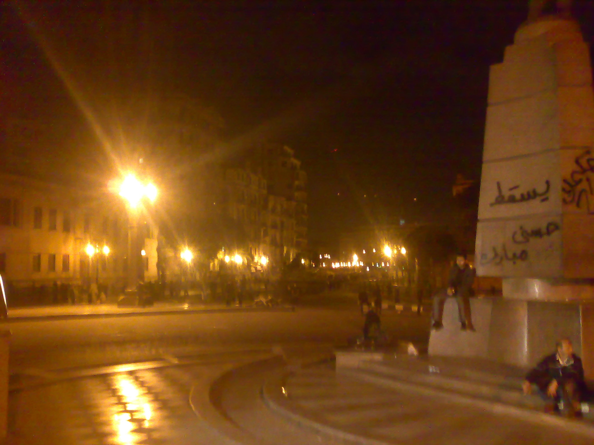 a group of people are sitting on steps in the middle of a street