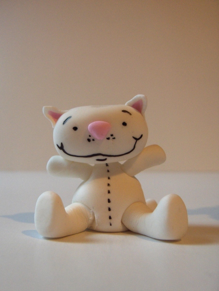 a white stuffed toy cat sitting on a counter