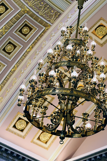 a lamp hanging from a golden chandelier in a room