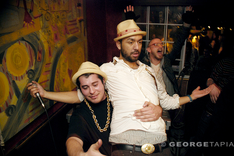 two young men pose for a picture while one of them has his hands up