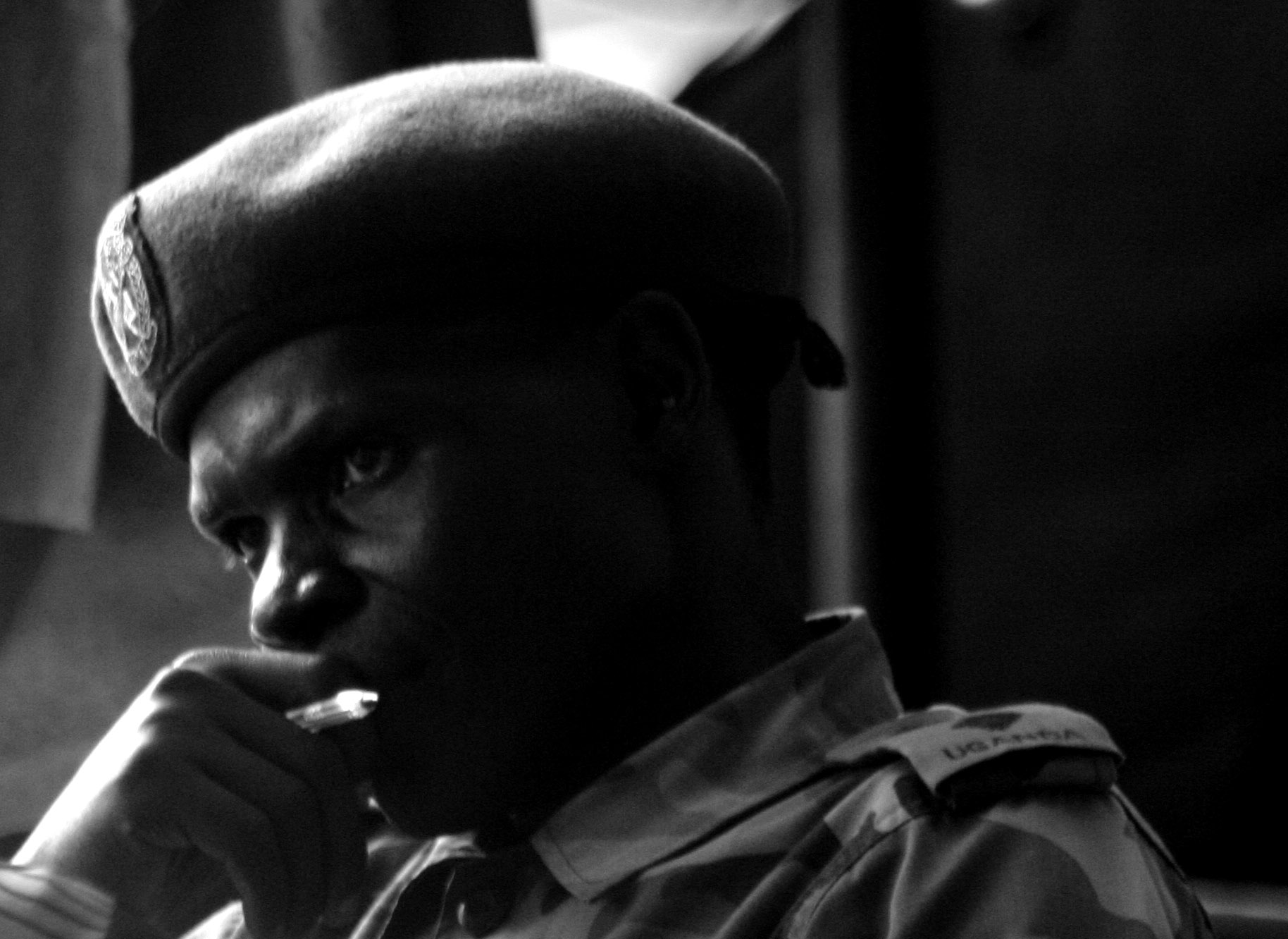 a man with a military style cap sits and talks on his cellphone