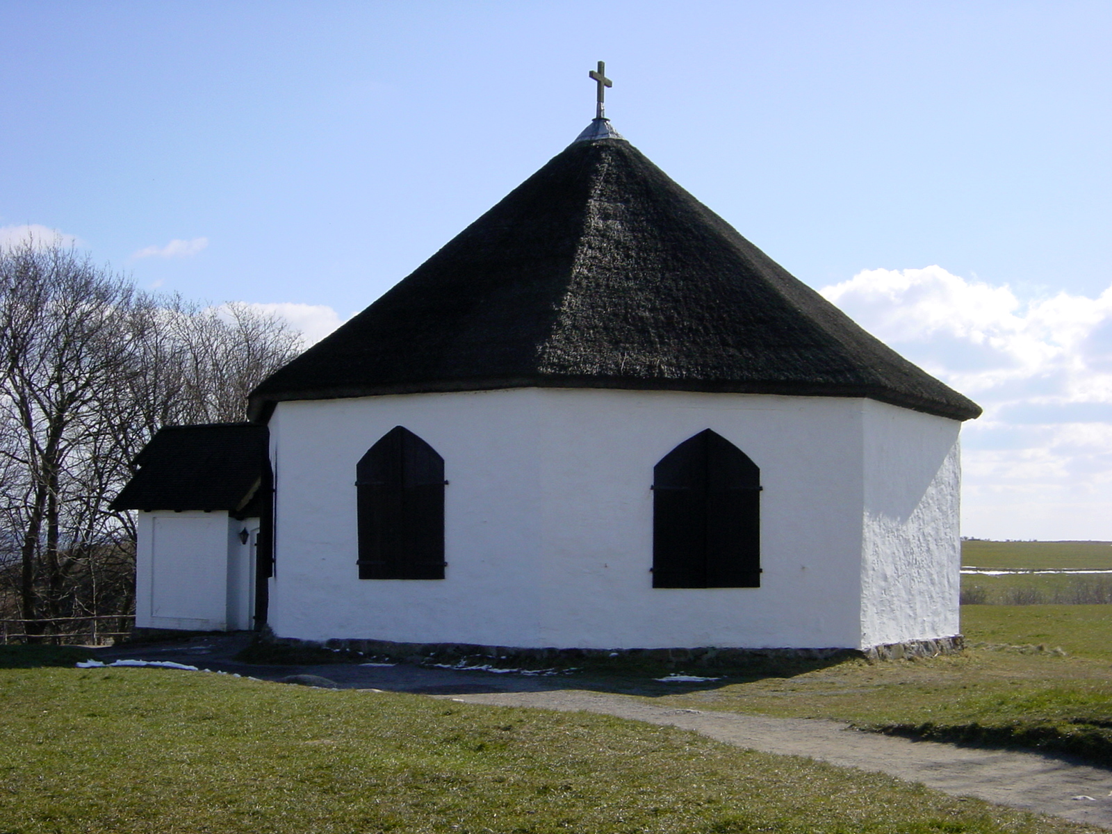 an old church has two large windows and is built into the side of it