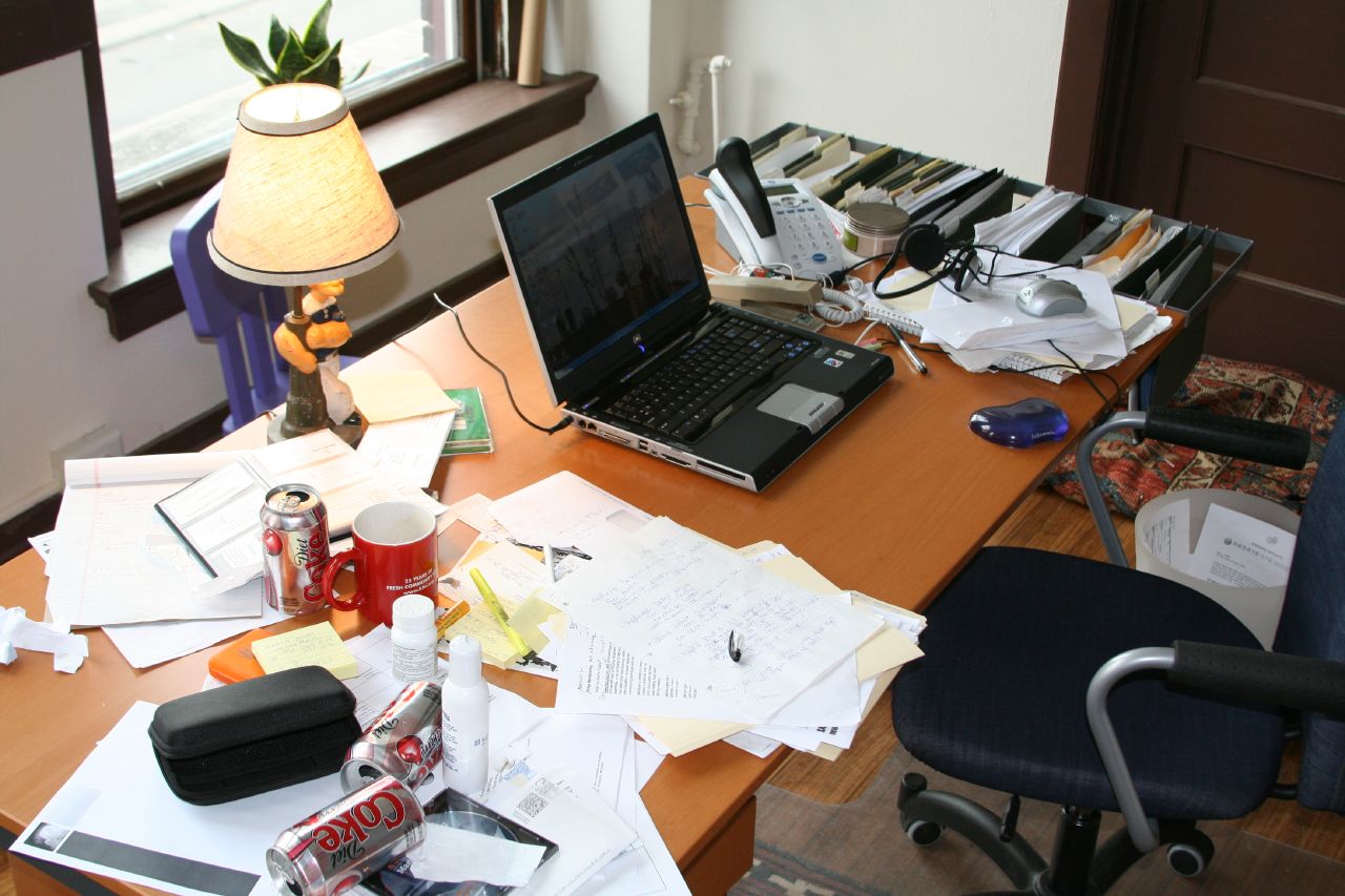 an office desk has papers, laptop and other items on it