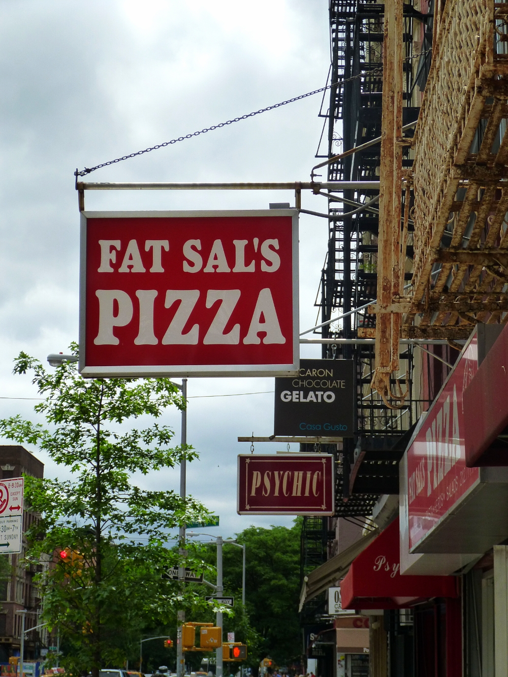 a fast food pizza restaurant sign hanging from the side of a building