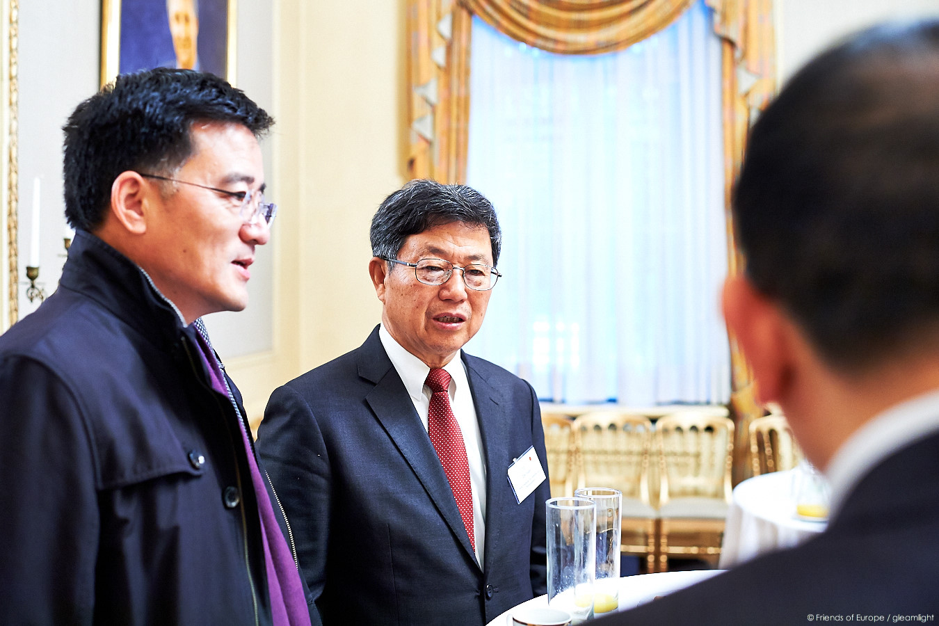 two men are speaking to each other at a formal function