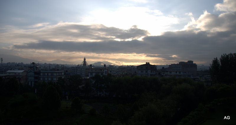 the sun is rising over some buildings, trees and other town