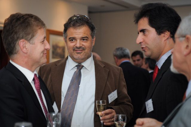 several men are talking around with wine glasses