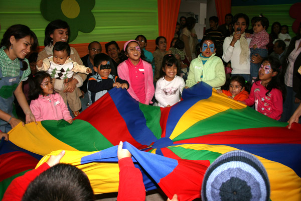 a crowd of people standing around a rainbow colored parachute